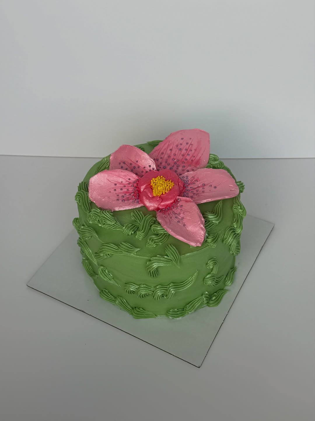 Green textured cake topped with a large pink orchid, Austin TX
